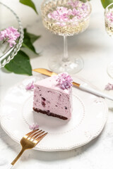 a piece of mousse cake, Delicious dessert blueberry tart with fresh berries with a bouquet of purple blooming lilacs, vertical image place for text