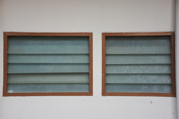 Ventilated louvered windows with wooden frames and opaque glass shutters.
