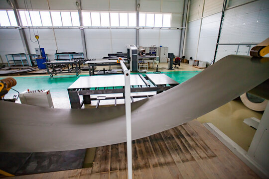 Aktau, Kazakhstan - May 05, 2012: Roll of sheet metal. Two workers and CNC laser cutting machine on background. Production of special electric equipment. RIG Ltd.