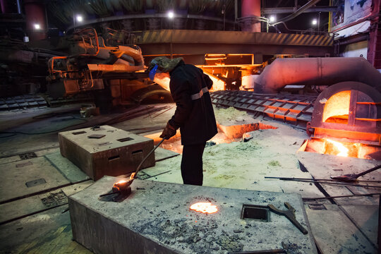 Temirtau, Kazakhstan - June 08, 2012: Arcelor Mittal metallurgy plant. Steel manufacturing in Smelter. Metallurgist take samples of steel. Electric arc furnace on background.