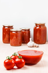 Fototapeta na wymiar Tomato sauce in a glass bowl. Tomato sauce in cans. Ripe tomatoes and garlic