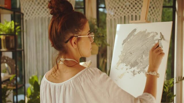 A Young Beautiful Woman Working At Picture Using Oil Paints And Palette-Knife Creates Modern Art, An Independent Freelance Businesswoman Relaxes In Her Free Time After Work, In An Art Studio In Sunset