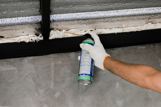 Human hand in white glove are caulking roof leaks with canned caulk foam.