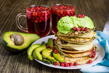 Pancakes with avocado ice cream. Sliced avocado. Lingonberry juice and berries from fruit drink.