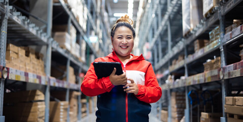 Plus size female worker inspecting box of products while working in large warehouse