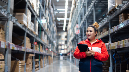 Plus size female worker inspecting box of products while working in large warehouse - obrazy, fototapety, plakaty
