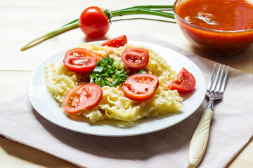 Pasta with fresh tomatoes and onions on a white plate.