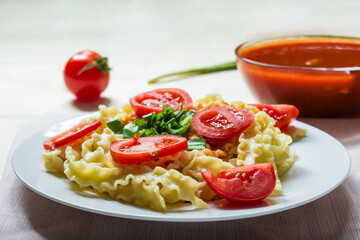 Pasta with fresh tomatoes and onions on a white plate.