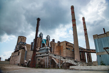 Panorama of old Soviet cement plant. Down-up perspective view. Buildings, silos, conveyors and smoke stacks. Temirtau, Kazakhstan.
