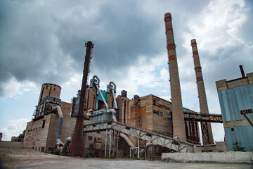 Panorama of old Soviet cement plant. Down-up perspective view. Buildings, silos, conveyors and...