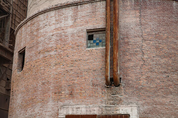 Close-up of Soviet cement plant silo tower. Cracked brick wall. Rusted pipes. Broken glass blocks windows. Temirtau, Kazakhstan.