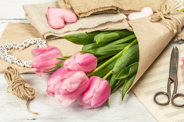 Bouquet of fresh pink tulips. Making spring floral decorations. Tools, vintage scissors, craft paper