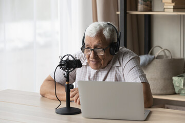 Elder radio host man in headphones and glasses speaking at professional microphone at laptop,...