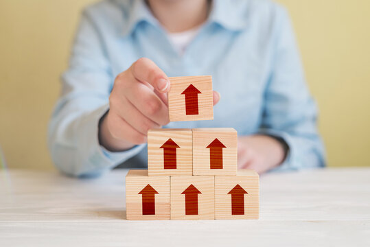 Hand picked wood cube block with arrow on top pyramid