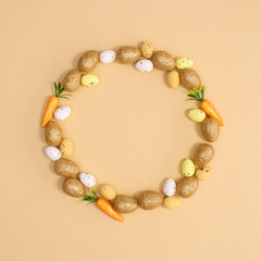 Creative copy space circle frame for Easter with eggs and carrots on pastel beige background. Flat lay minimal.