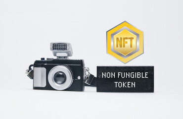 A picture of camera and wooden block written non fungible token with NFT symbol. Non fungible token concept.