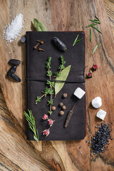 Notebook for recipes with spices, sugar, black salt, tonka bean on a wooden cutting board. Selective focus