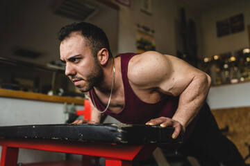 Fototapeta premium One man young adult bodybuilder doing push ups exercise training in the gym side view