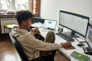 Absent-minded african american broker vaping while watching data index chart stock market