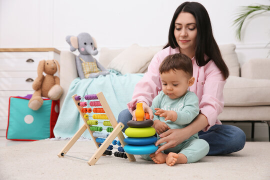 Cute baby boy playing with mother and toys on floor at home