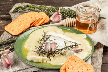 Melted Rougette cheese with fresh rosemary and garlic. Crunchy crackers, honey