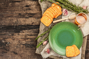 Table setting for a delicious snack in rustic style. Plate, crackers, garlic, fresh rosemary