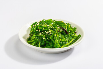 Chuka Seaweed Salad with sesame seeds isolated on white background. Trendy hard light, dark shadow