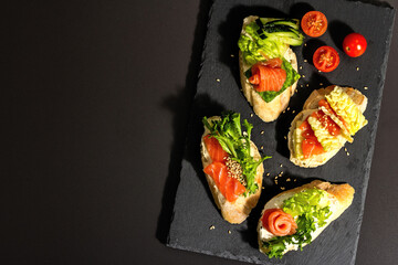 Assorted open sandwiches with salted salmon, cream cheese, salad leaves and cucumber. Seafood