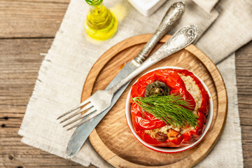 Homemade meat and rice stuffed bell peppers. Olive oil, sauce, cutlery on vintage wooden background