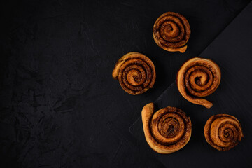 freshly baked chinabons lie on a stone board on a black stucco background. Top view. Artistic dark layout with copy space