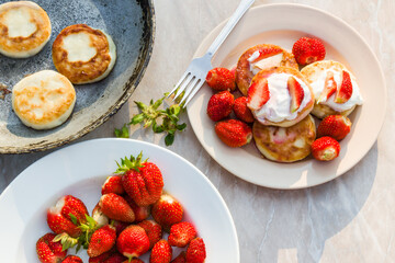 Cheesecakes with strawberries and sour cream. Breakfast in nature. Traditional Russian and Ukrainian dish.