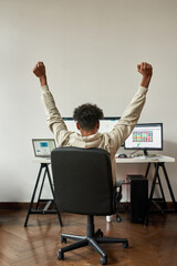 Back view of african american trader hands up watching stocks graph climb higher