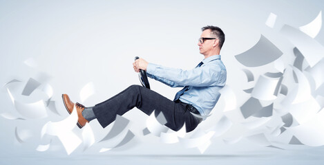 Confident businessman in shirt, tie and glasses flies through sheets of white paper holding a car...