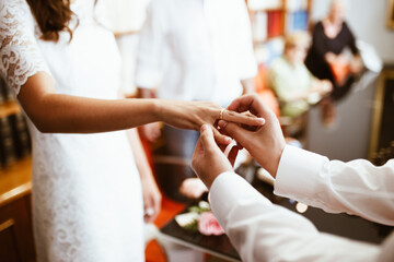 Obraz na płótnie Canvas Man putting wedding ring on woman finger. Exchange Wedding rings. happy groom and bride. Wedding day concept.