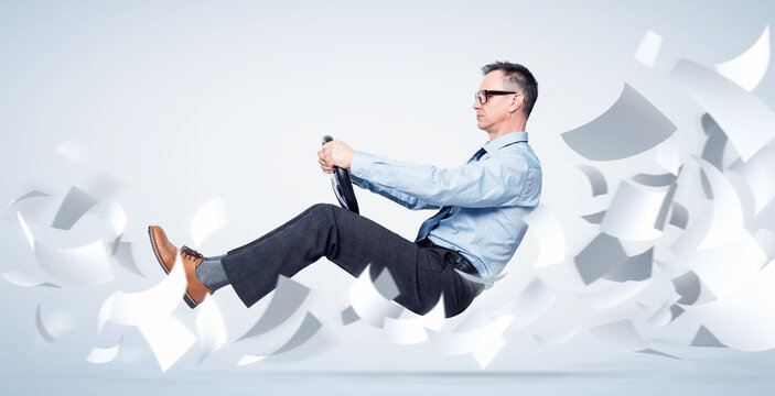 Confident businessman in shirt, tie and glasses flies through sheets of white paper holding a car steering wheel, on blue background. Office movement