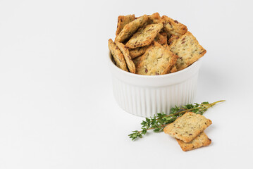 Square crackers with herbs, flax seeds and spices in white form on white background. Herbal crunchy diet cookies with green thyme