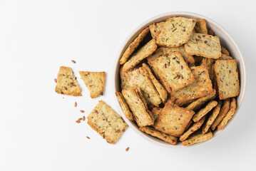 Square diet cookies with rosemary, leenseed and spices  in a light plate on white background. Crunchy herbal crackers top view