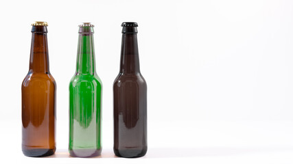 Three bottles of green, brown and black beer with a white background