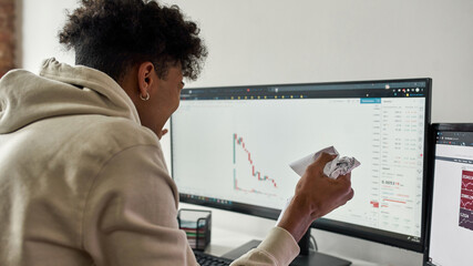 African american trader crumples paper and yelling watching stocks graph