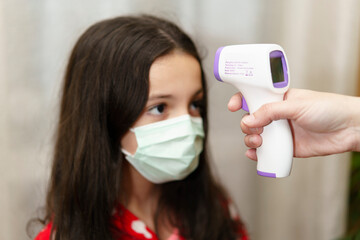 Mother taking her daughter's temperature with thermometer