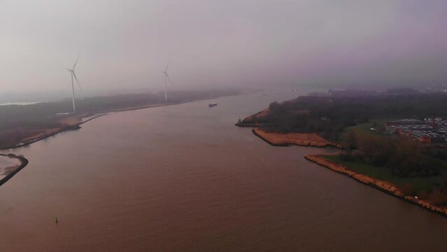Aerial Flying Over Oude Maas With Wind Turbines Seen Through Misty Clouds In Distance In Barendrecht. Dolly Forward 