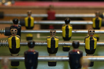 Table football in which you can see players from two teams, some blue and in the foreground a player with a black and yellow striped shirt