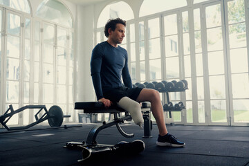 Man with prosthetic leg sitting on a gym bench . He is mentally preparing for his fitness session