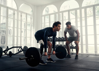 Disabled athlete weightlifting with his coach in the gym. Man with prosthetic leg being coached by his instructor