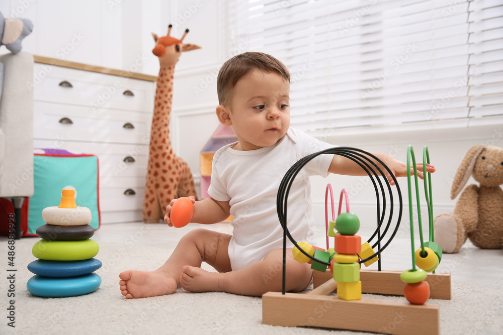 Sticker Cute baby boy playing with toys on floor at home