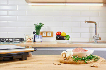 Barbecue preparing in the kitchen interior. Electric grill barbecue and meat on kitchen table.