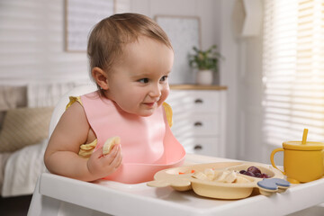 Cute little baby wearing bib while eating at home