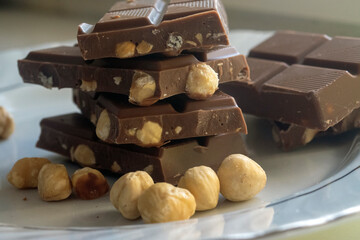 Chocolate and hazelnuts. Pieces of chocolate with hazelnuts on a white plate. 