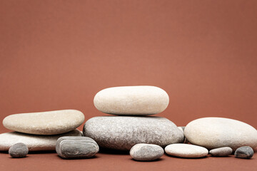 Fototapeta na wymiar heap of stones, pebbles on brown background, podium for product presentation
