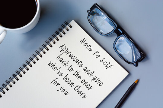 Motivational quote on notepad with coffee and reading glasses on a desk.